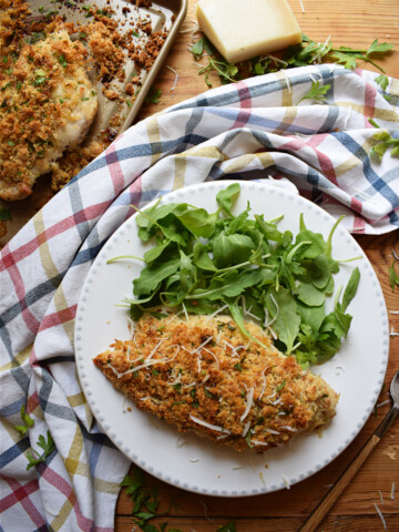 Parmesan chicken on a plate with a salad.