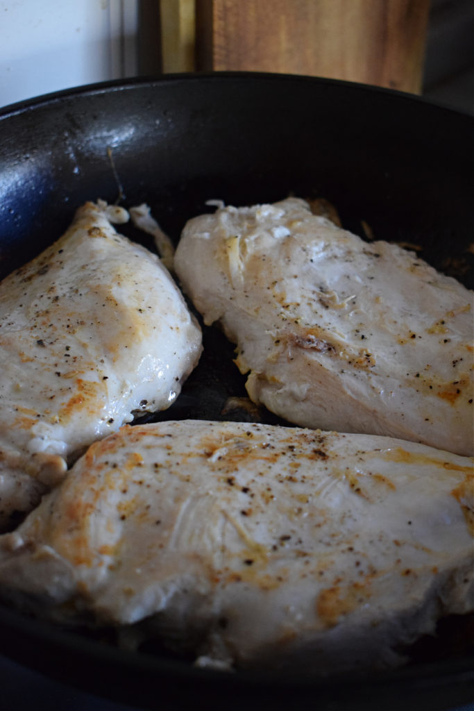 Searing chicken in a skillet for parmesan chicken.