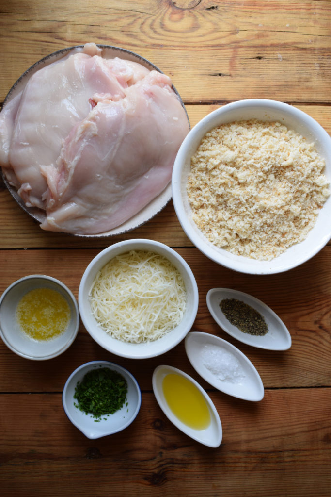 Ingredients on a wooden board to make parmesan crusted chicken.