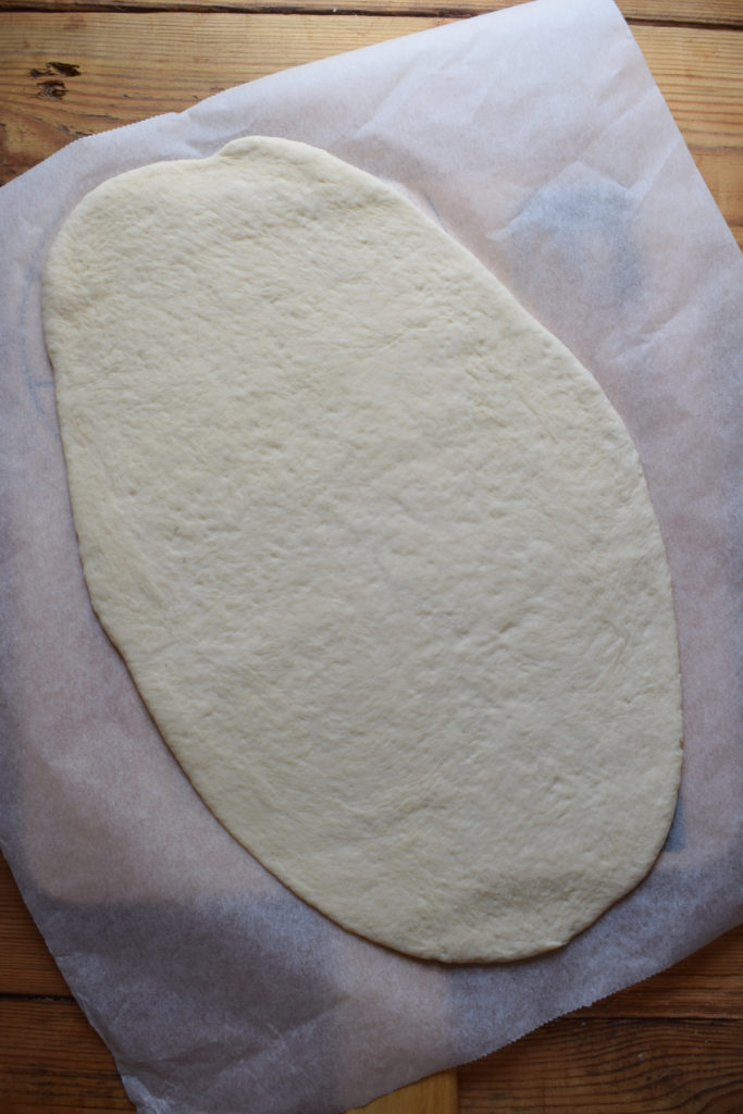 Pizza dough on a sheet of parchment paper.