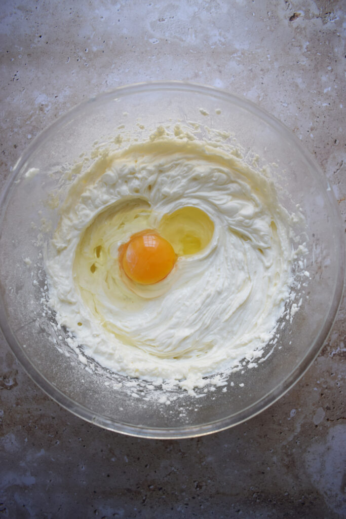 Adding eggs to a cream cheese filling.