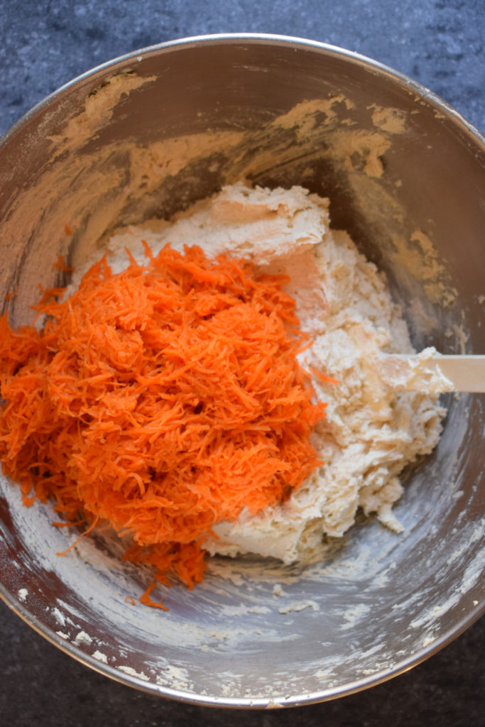 Shredded carrots in a bowl with cake batter.