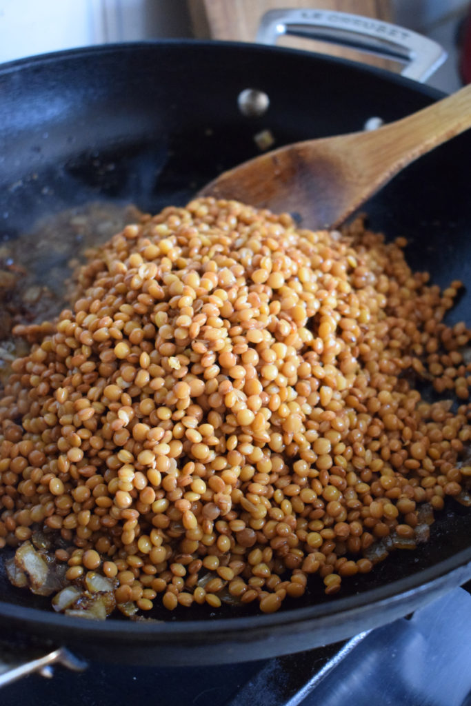 Adding lentils to a skillet.