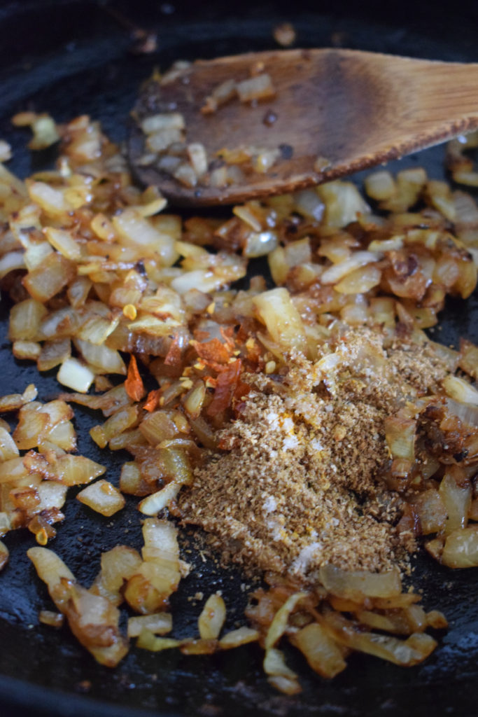 Adding spices to onions on the stove top.