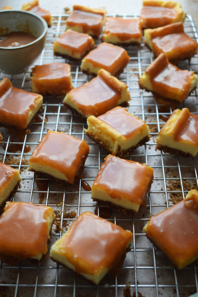 Caramel cream cheese squares on a cooling rack.