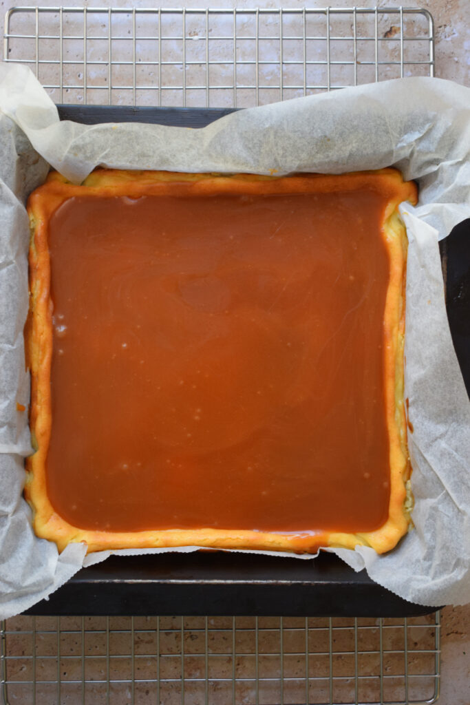 Caramel cheesecake squares in a baking tin.