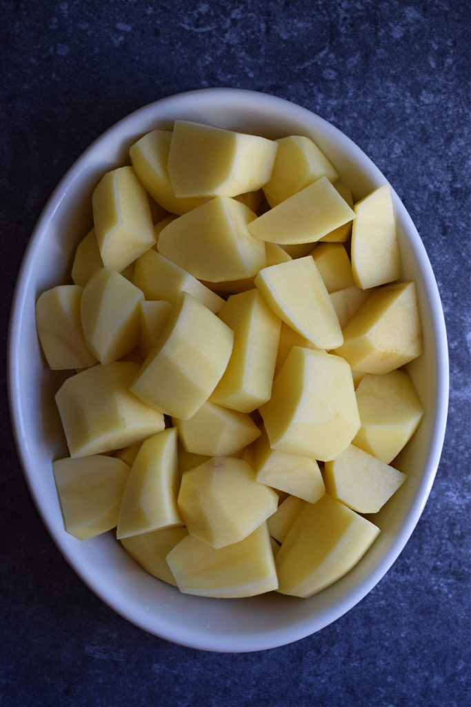 Peeled and cut potatoes in a white dish.