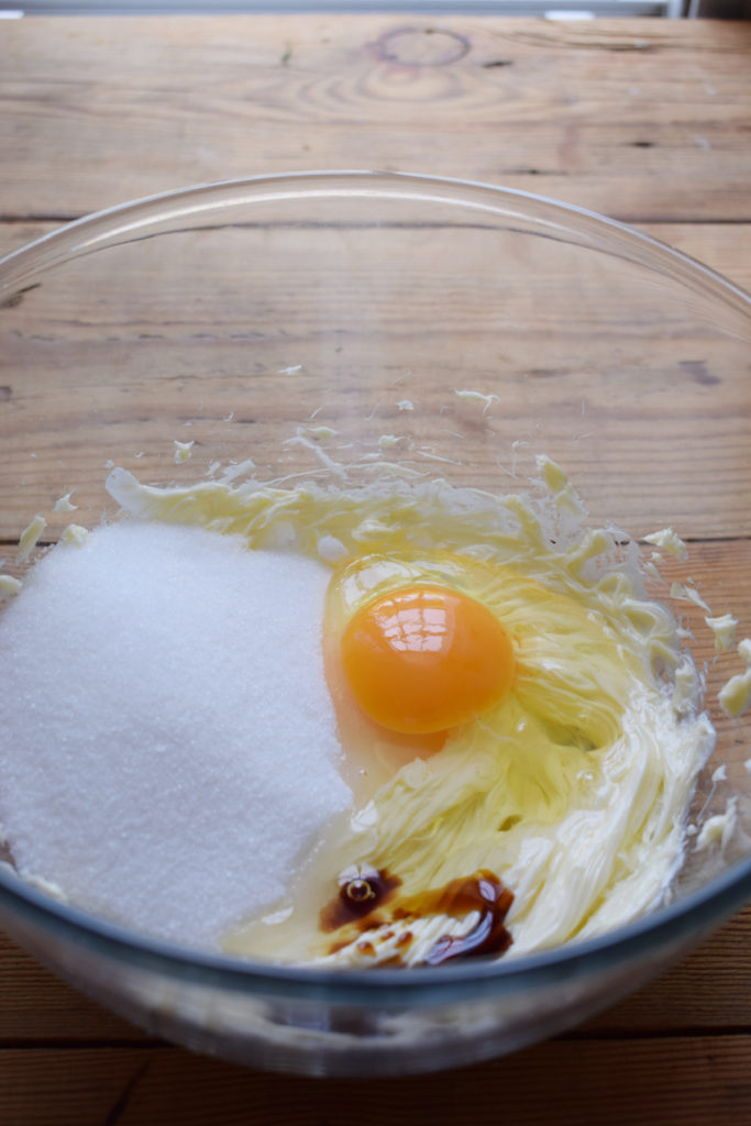 Sugar, butter, eggs and vanilla in a glass bowl.