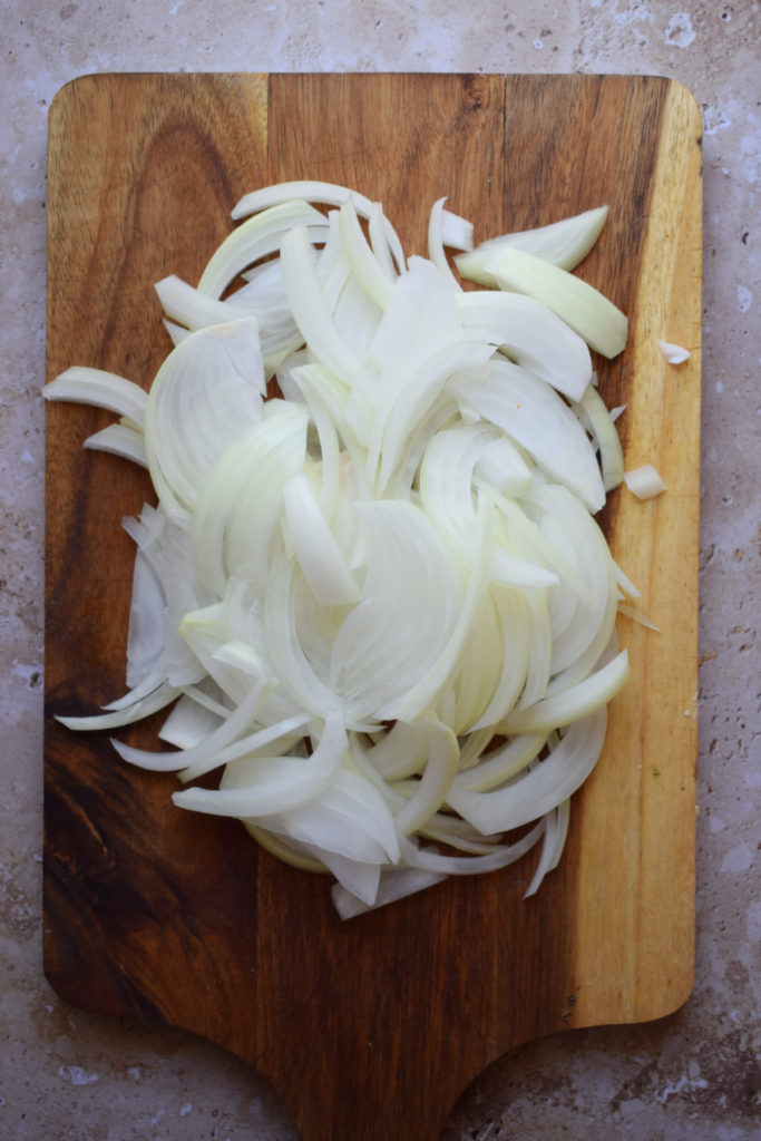 Sliced onions on a wooden board.