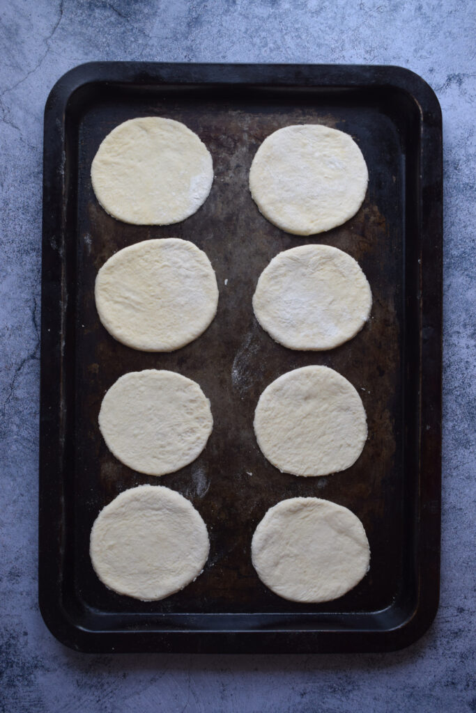 Pizza dough circles on a baking tray.