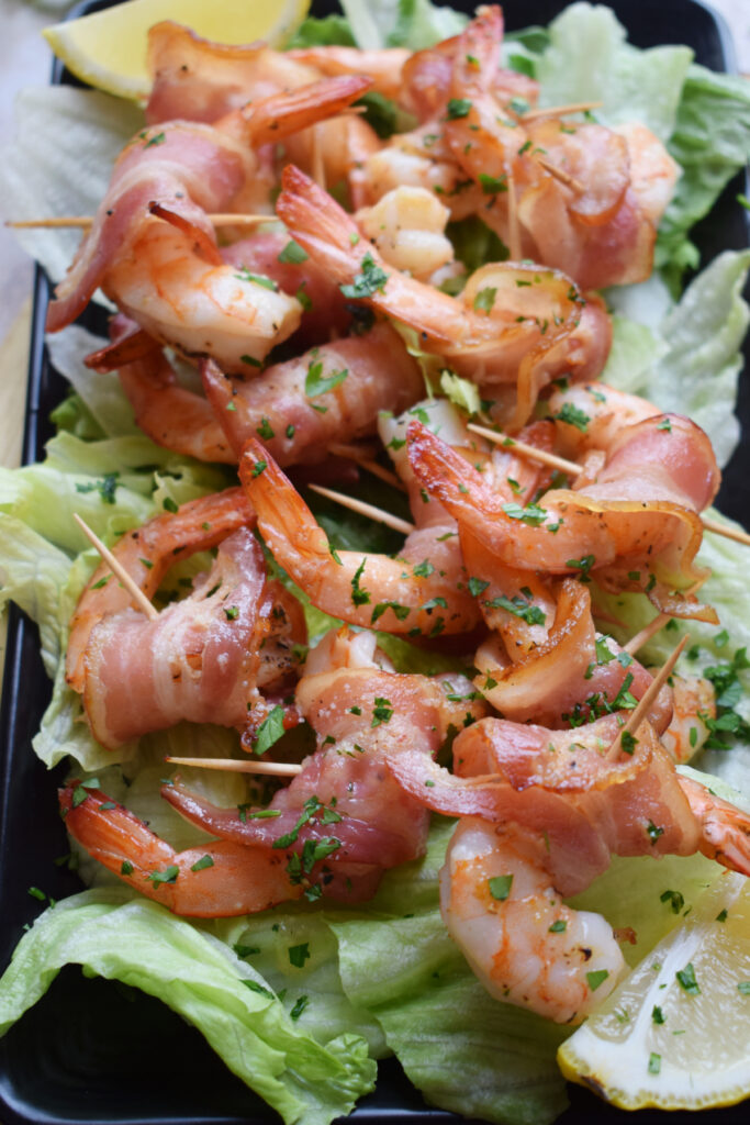 Bacon wrapped shrimp on a bed of lettuce.
