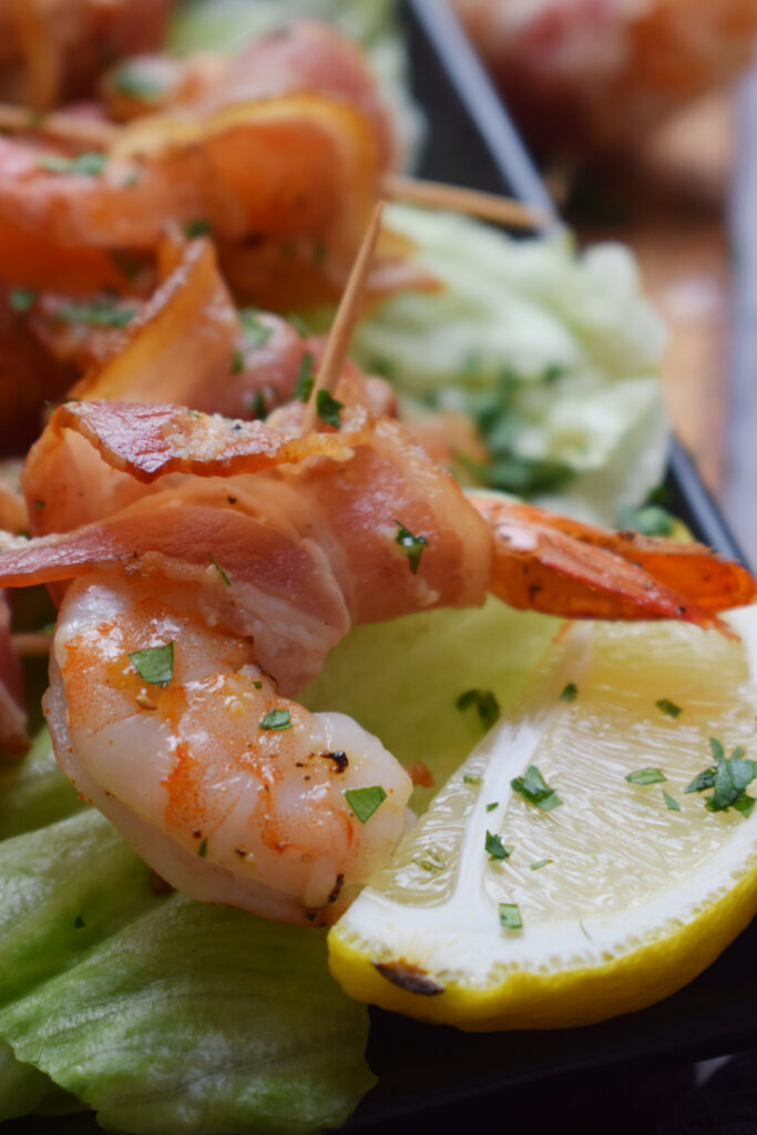 Shrimp wrapped in bacon with a lemon wedge.