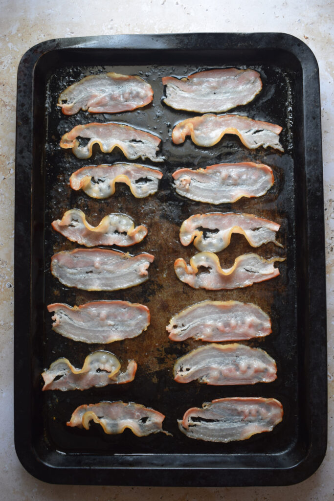 Cooked bacon on a baking tray.
