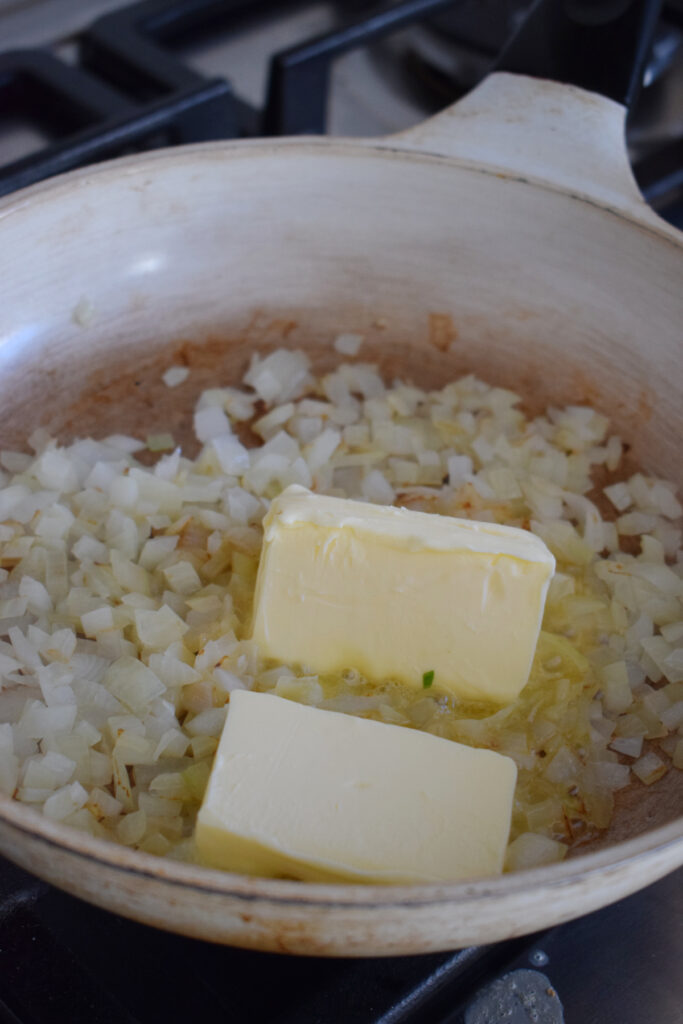 Adding butter to onions in a skillet.