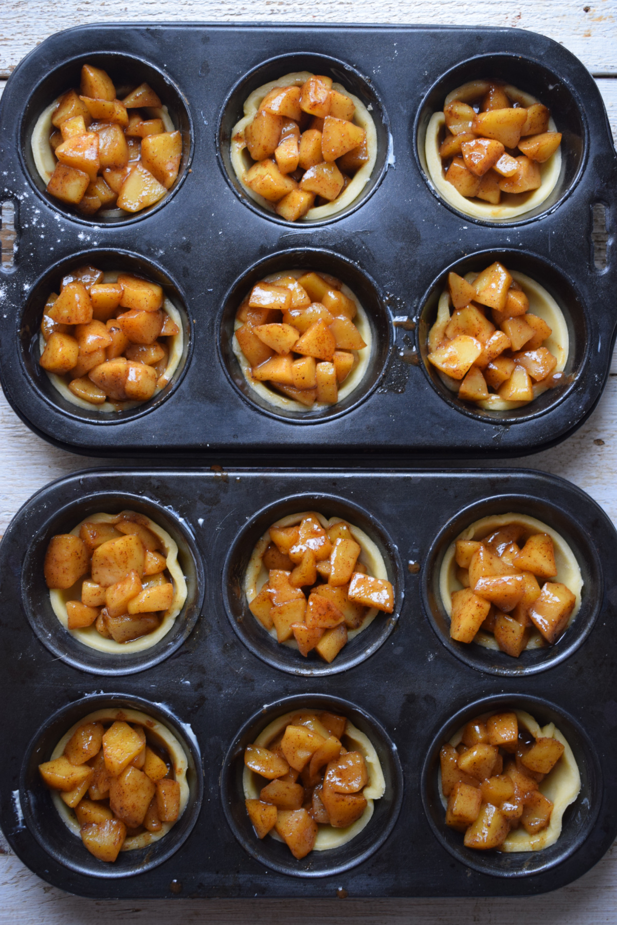 Making mini apple pies in muffin tins.
