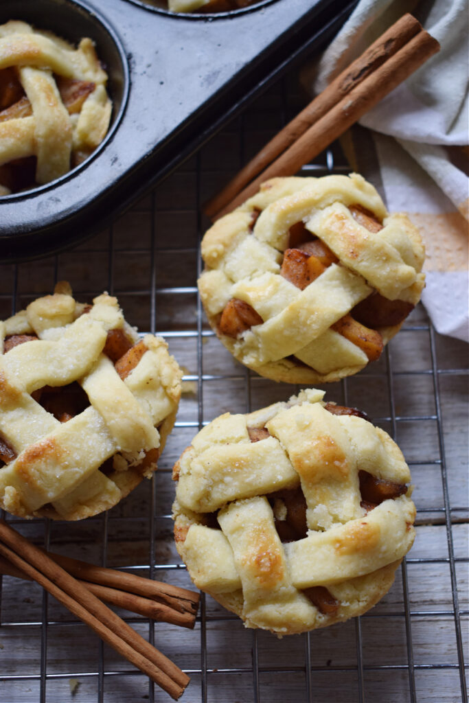 Close up of three mini apple pies on a cooling rack.