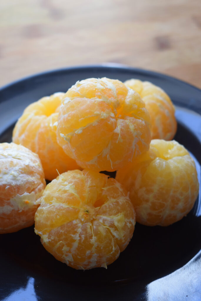 Peeled clementines on a black plate.