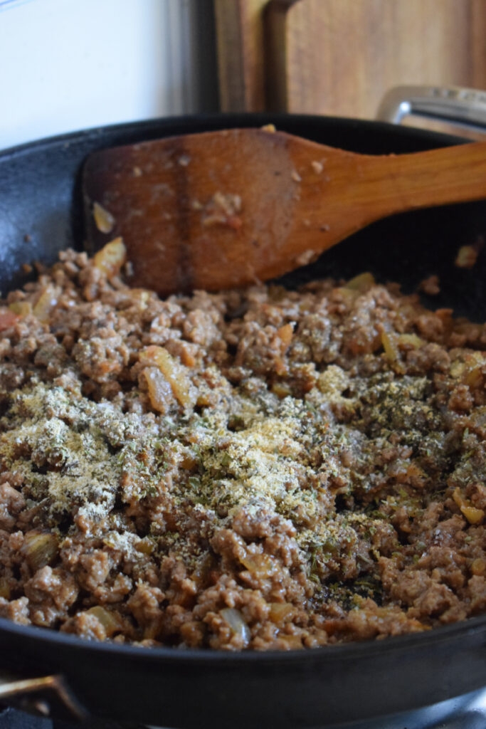 Adding seasonings to ground beef in a skillet.