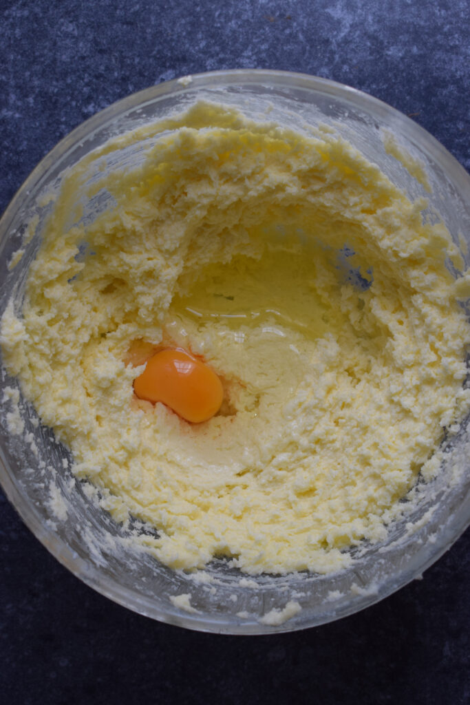 Adding eggs to cake batter in a glass bowl.
