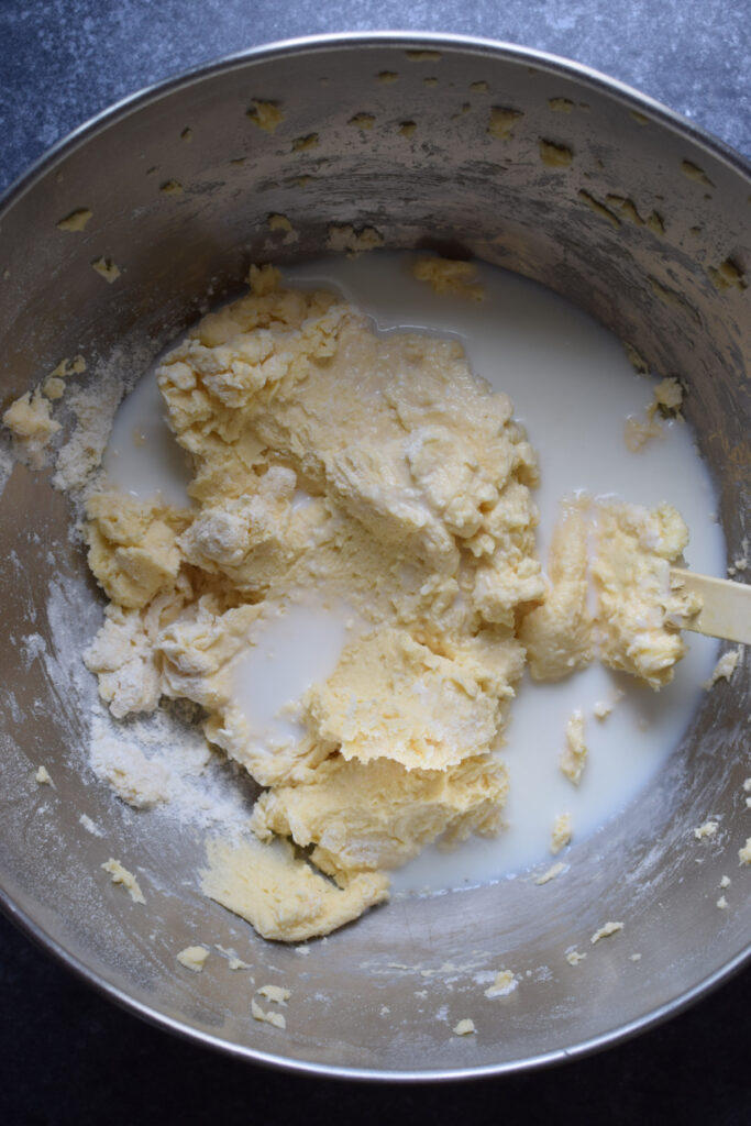 Adding milk to cake batter in a bowl.