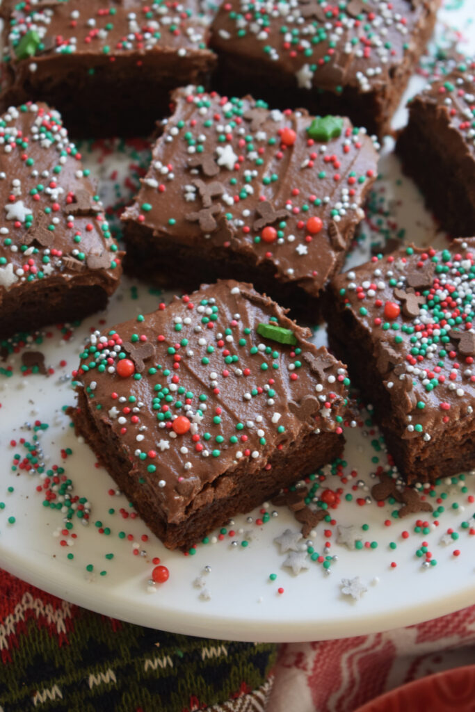 Chocolate brownies with sprinkles on a white serving tray.
