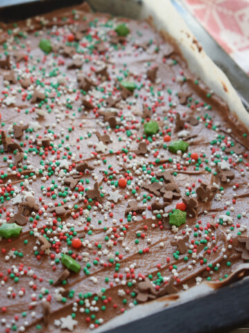 Brownies in a baking tray with frosting and sprinkles.