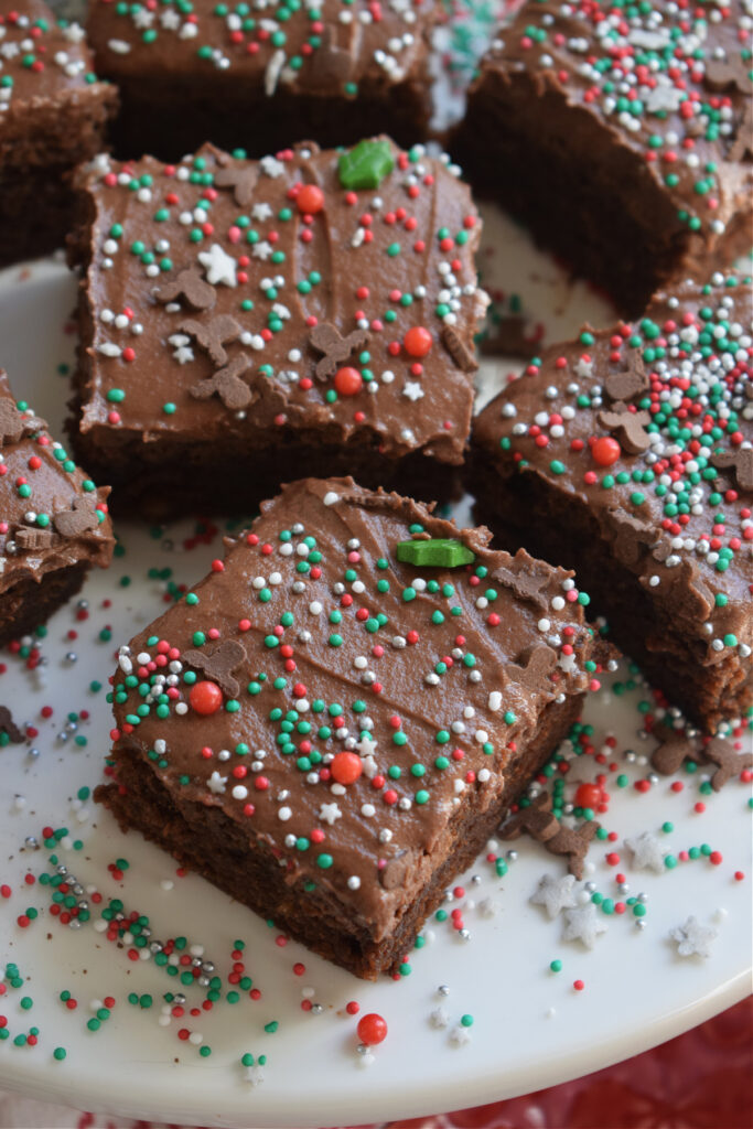 Chocolate frosted brownies with sprinkles on a plate.