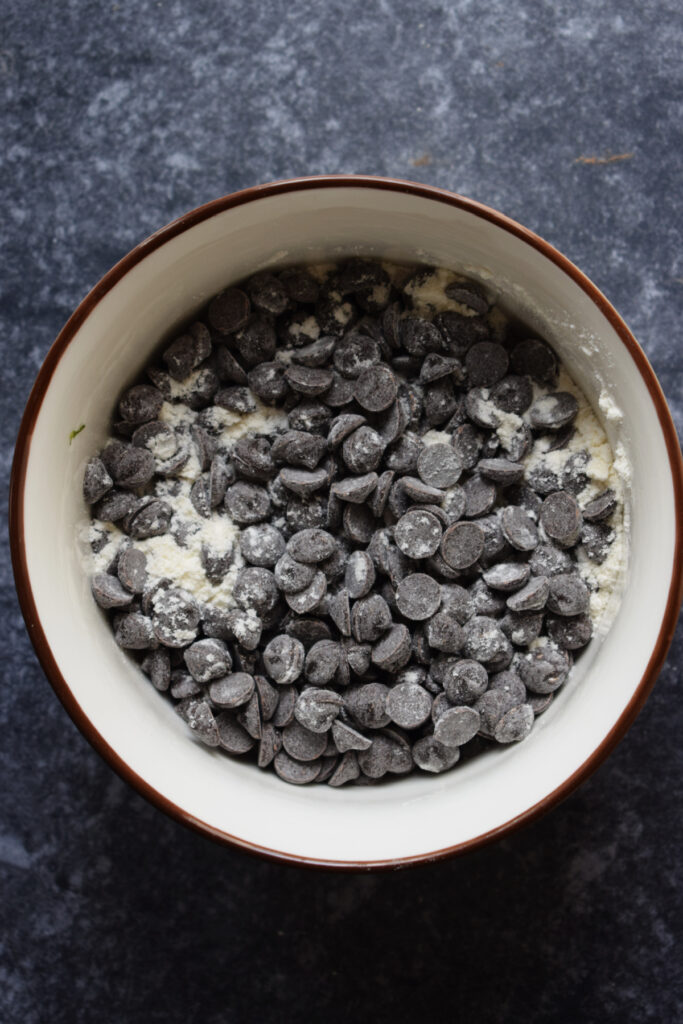 Chocolate chips tossed in flour in a bowl.