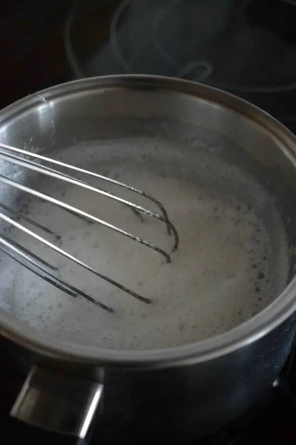 Whisked egg whites and sugar in a saucepan.