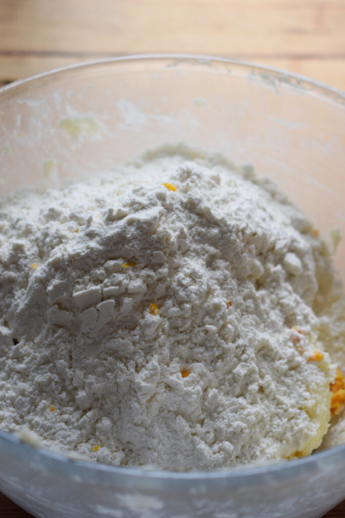 Adding flour to a glass bowl to make cookie dough.
