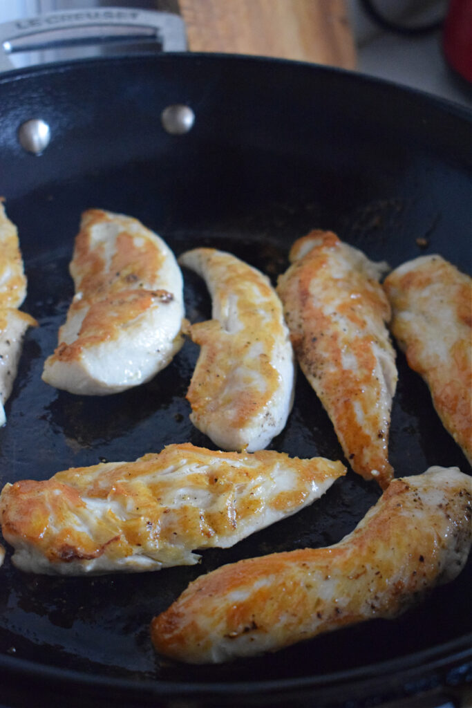 Cooked chicken tenders in a skillet.