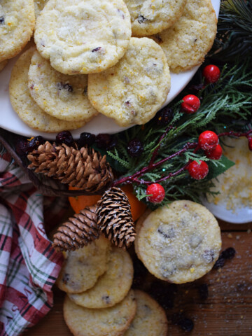 Cranberry and orange cookies on a wooden background with Christmas holly.