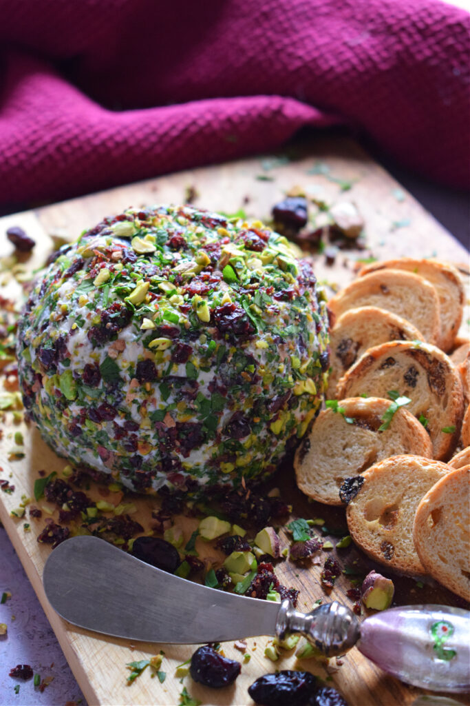 Cranberry goat cheese ball on a board with crackers.