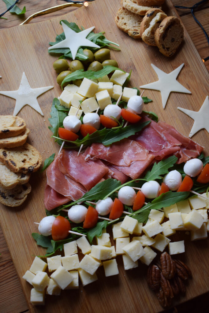 Ham, cheese, olives and tomatoes on a board.