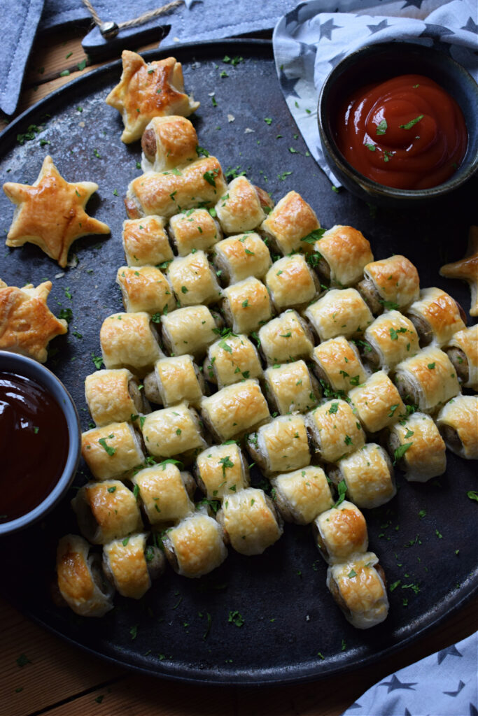 A sausage roll Christmas tree on a tray with dips.
