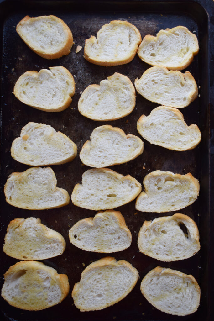 Baguette slices on a baking tray.