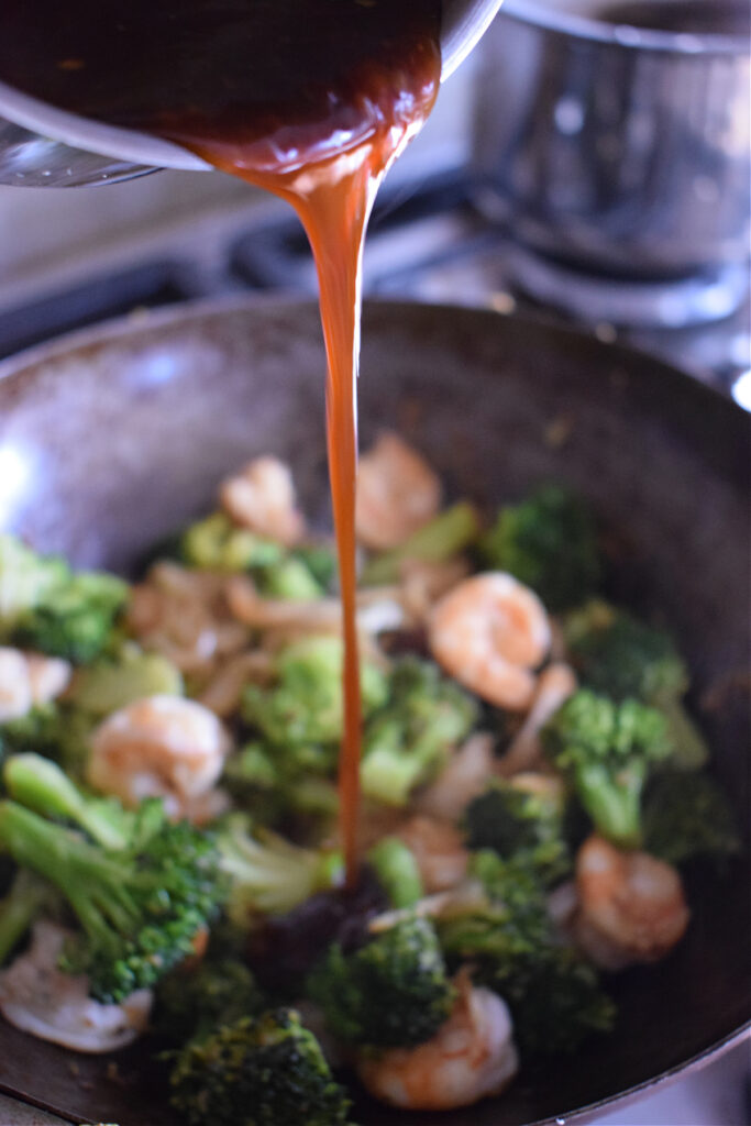 Adding sauce to a stir fry in a wok.