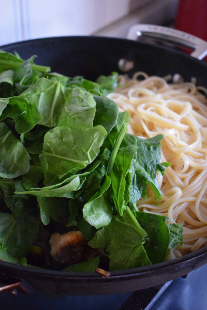 Spinach and spaghetti in a skillet.