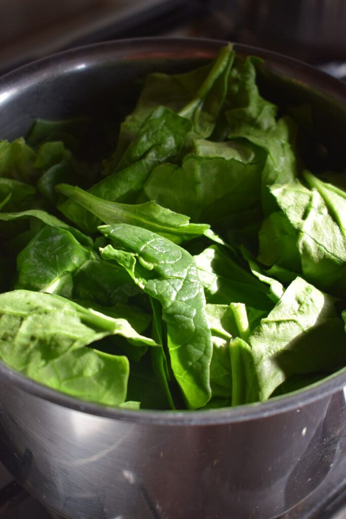 Adding spinach to a pot of soup.