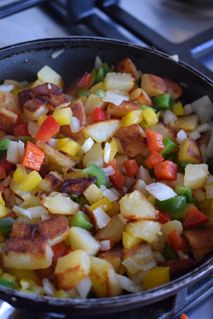 Cooking peppers and potatoes in a skillet.