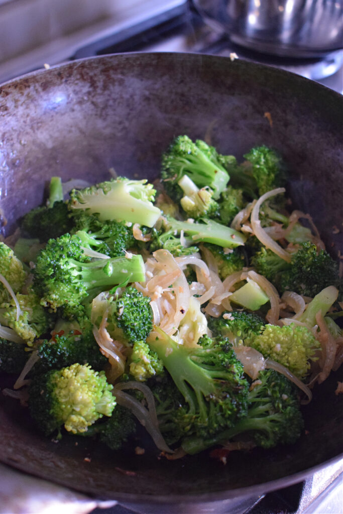 Cooking broccoli and onions in a wok.