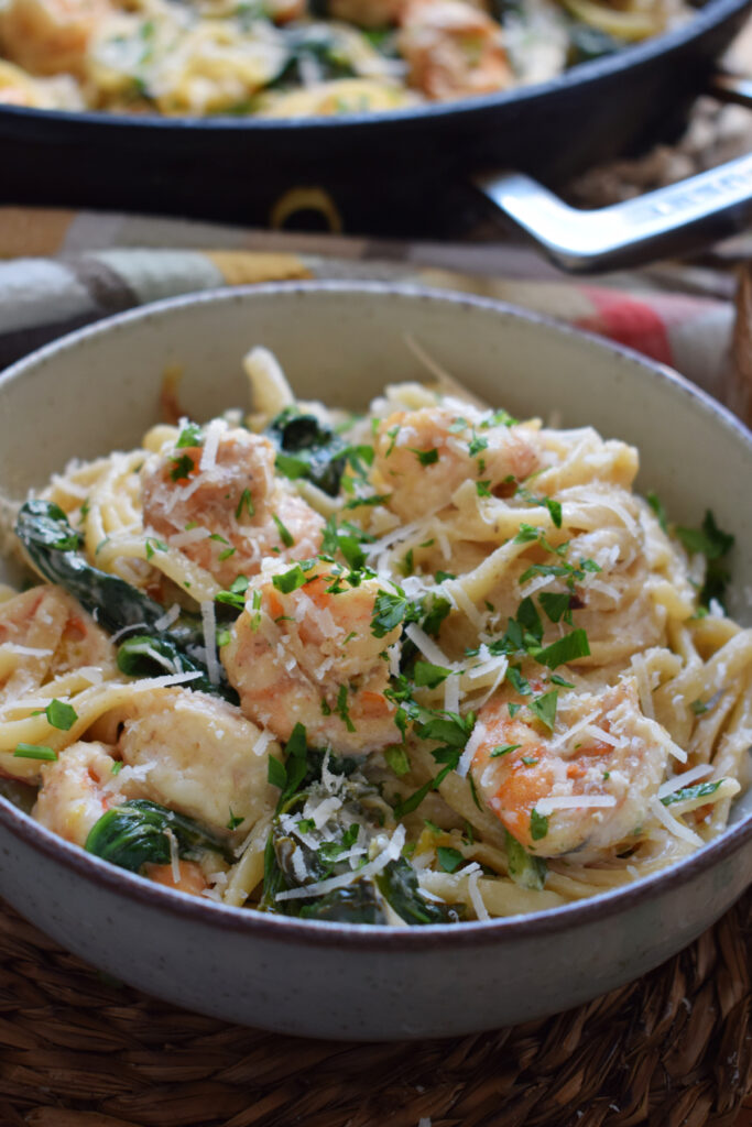 Pasta with shrimp and spinach in a bowl.