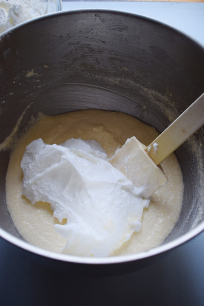 Folding egg whites into lemon pudding mixture.