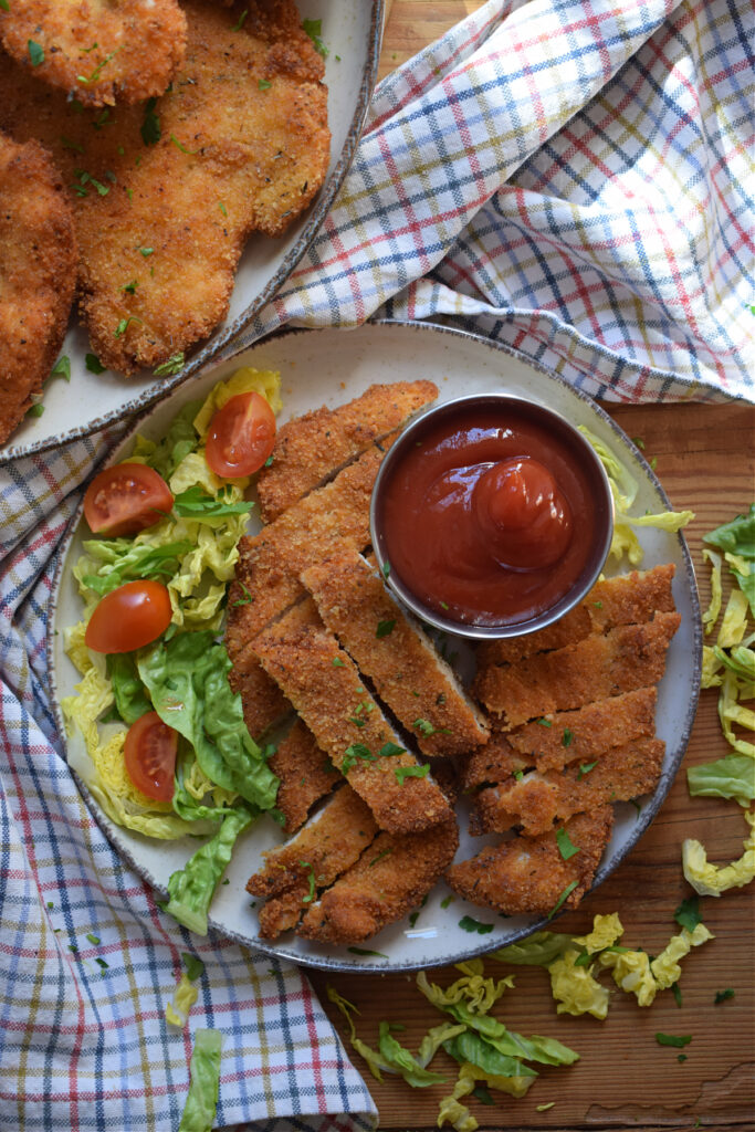 Fried chicken on a plate with dipping sauce and a small salad.