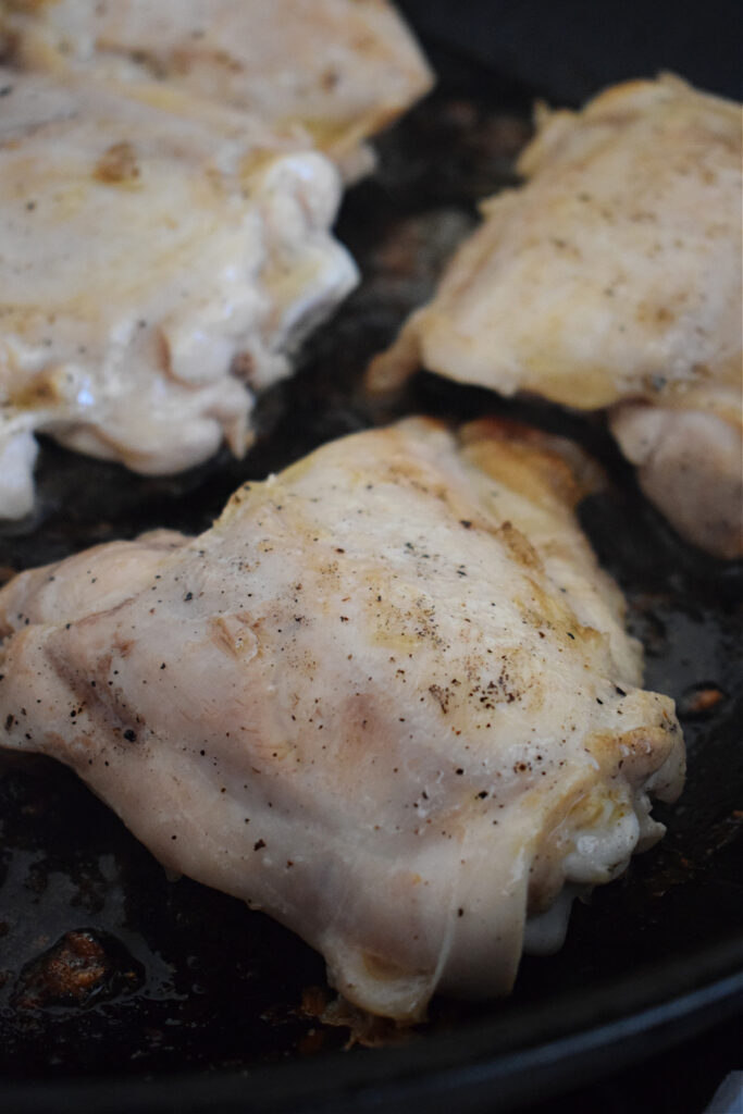 Close up of chicken thighs in a skillet.