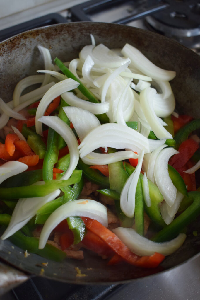Adding peppers to a wok.