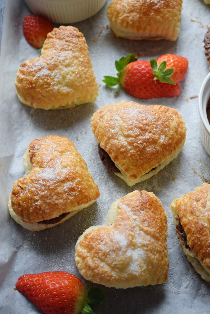 Filled pastry on a baking tray with strawberries.