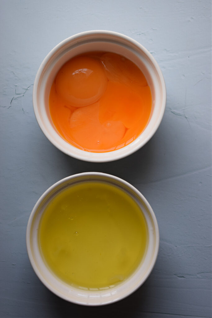 Egg yolks in a bowl and egg whites in a bowl.