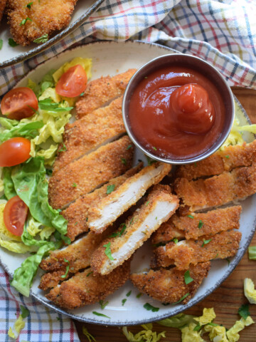Fried chicken pieces on a plate with dipping sauce.