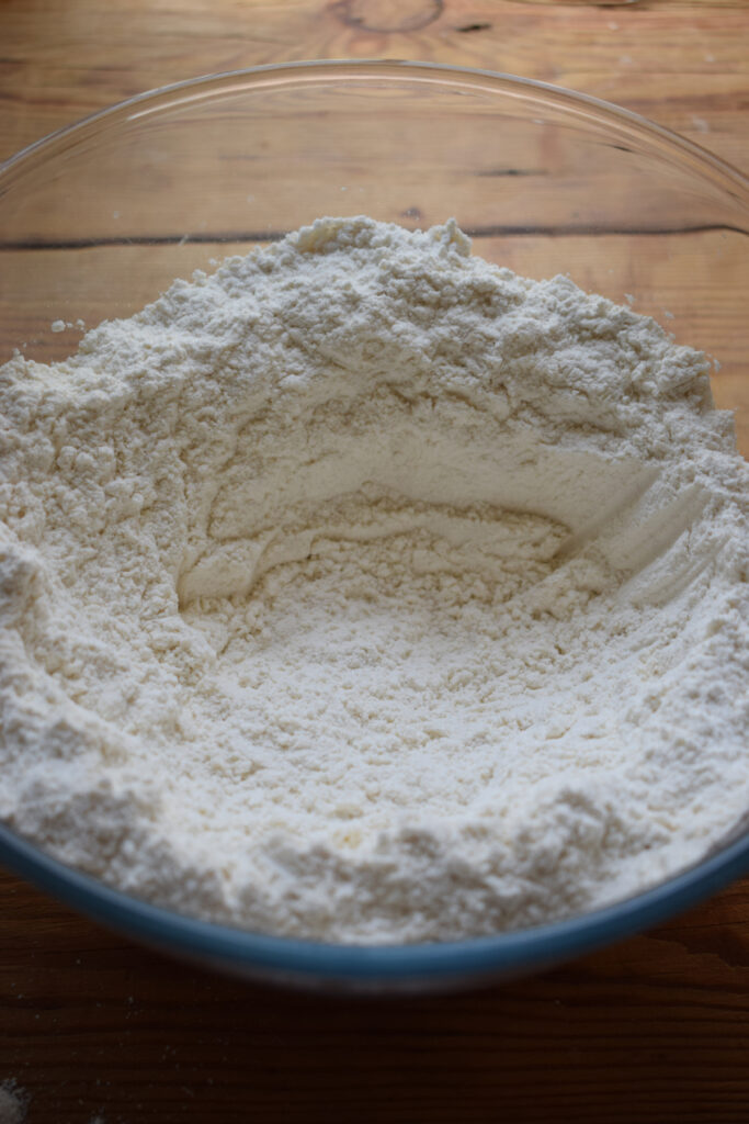 Making a well in the center of flour.